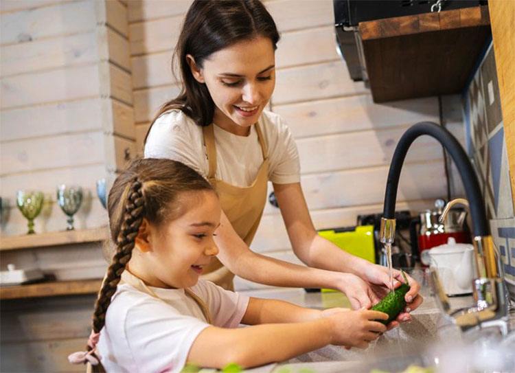 Mother and her child are washing a cucumber