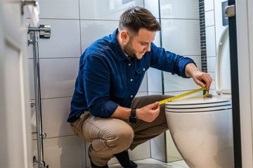 A man in blue shirt is showing how to measure a toilet