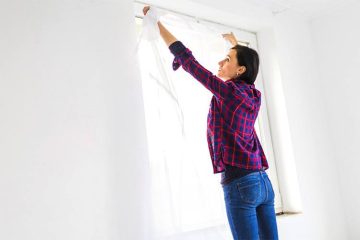 A women i showing how to measure a window for curtains