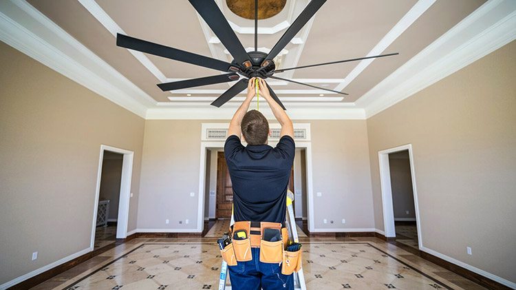 A worker is measuring a ceiling fan
